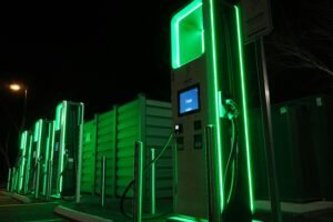 Green-lit electric vehicle fast-charging station at night