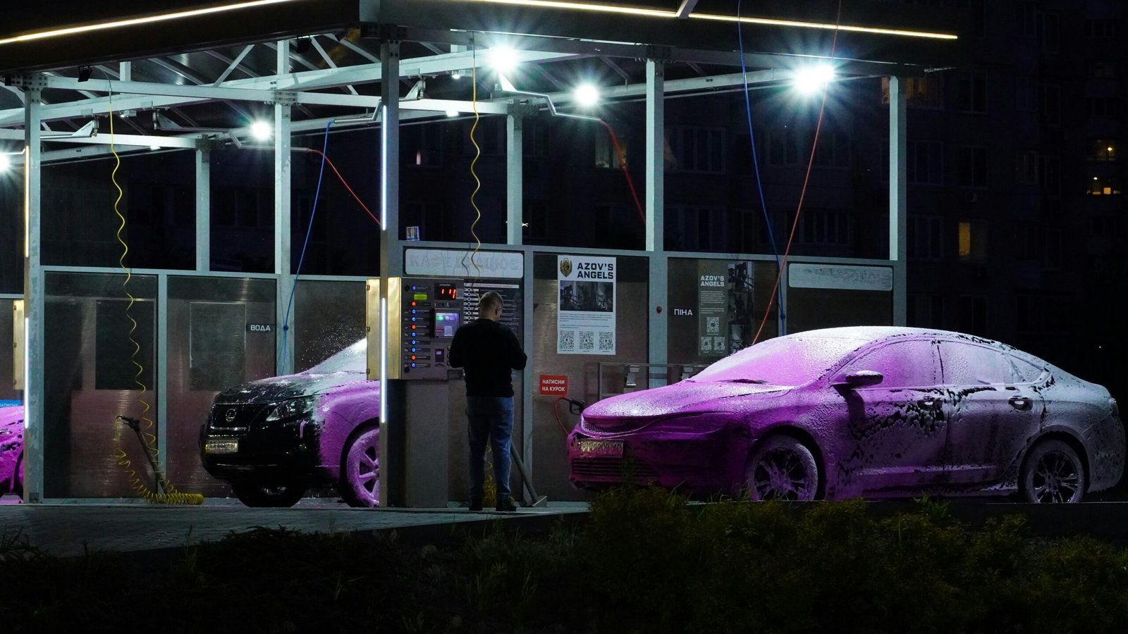Electric car parked beside illuminated public charging stations at night