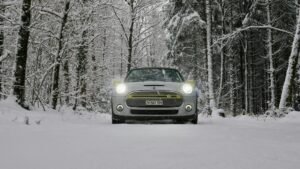 Electric car driving through a snowy forest on a cold winter morning