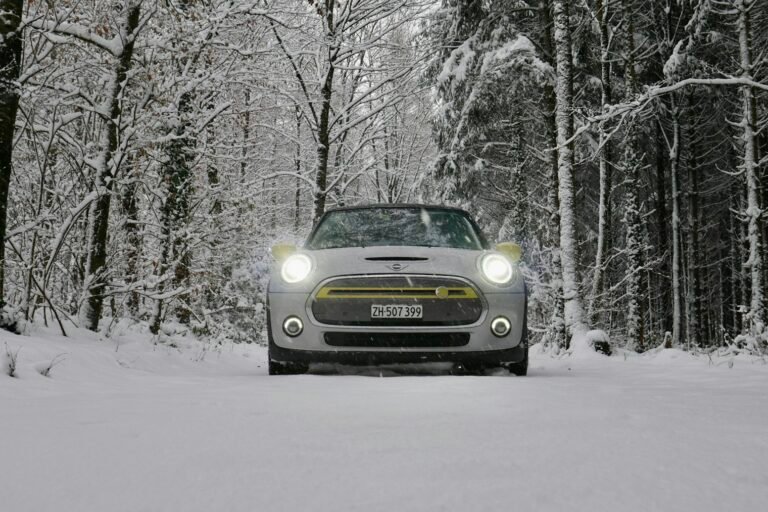 Electric car driving through a snowy forest on a cold winter morning