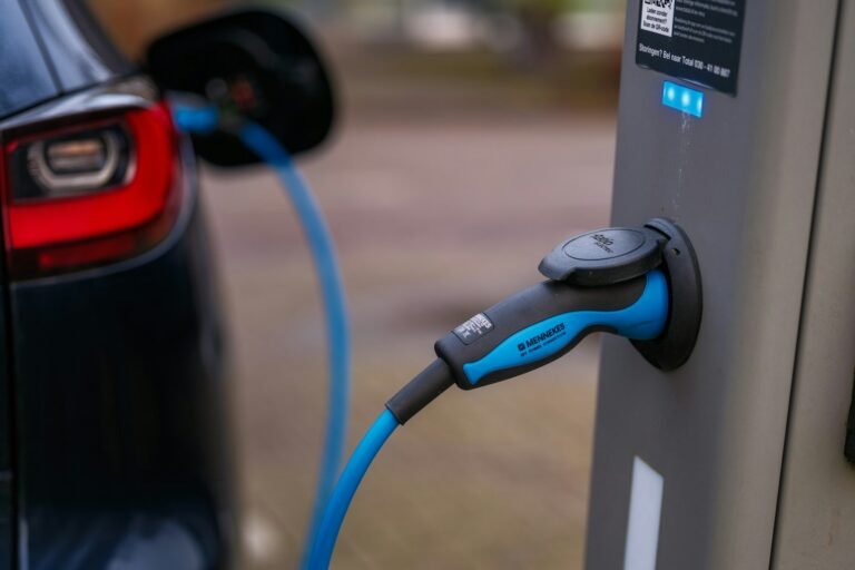 Blue electric vehicle charging connector plugged into a public charging station